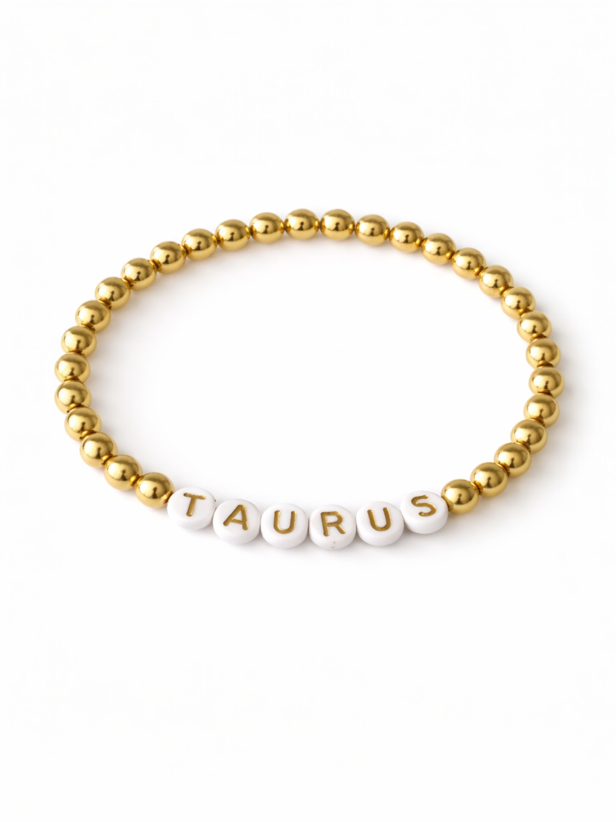 Gold bead bracelet with white letter beads spelling "TAURUS." Perfect for astrology enthusiasts.