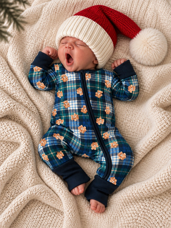 Baby in plaid onesie and a festive red and white hat yawns on a cozy blanket.