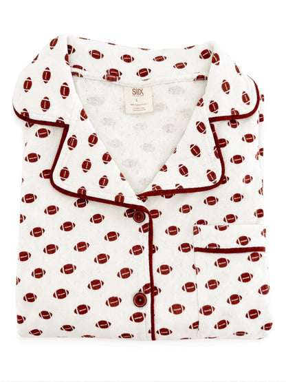 Folded white pajamas with red football prints and maroon piping, showcasing a classic design.
