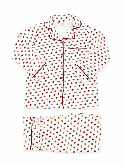 White pajama set with red and black patterned design and piped detailing. Includes a button-up shirt and pants.