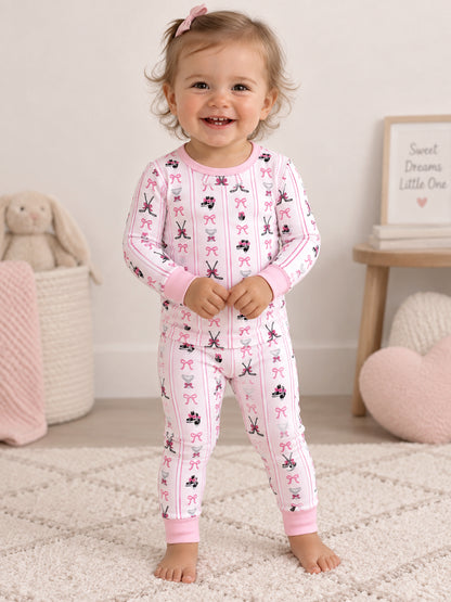 Smiling toddler in playful pink pajamas with fun patterns, standing on a soft rug.