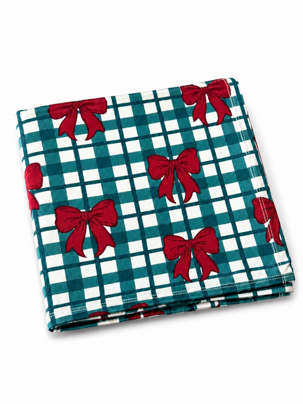 Folded tablecloth with a teal and white checkered pattern, featuring red bows throughout.