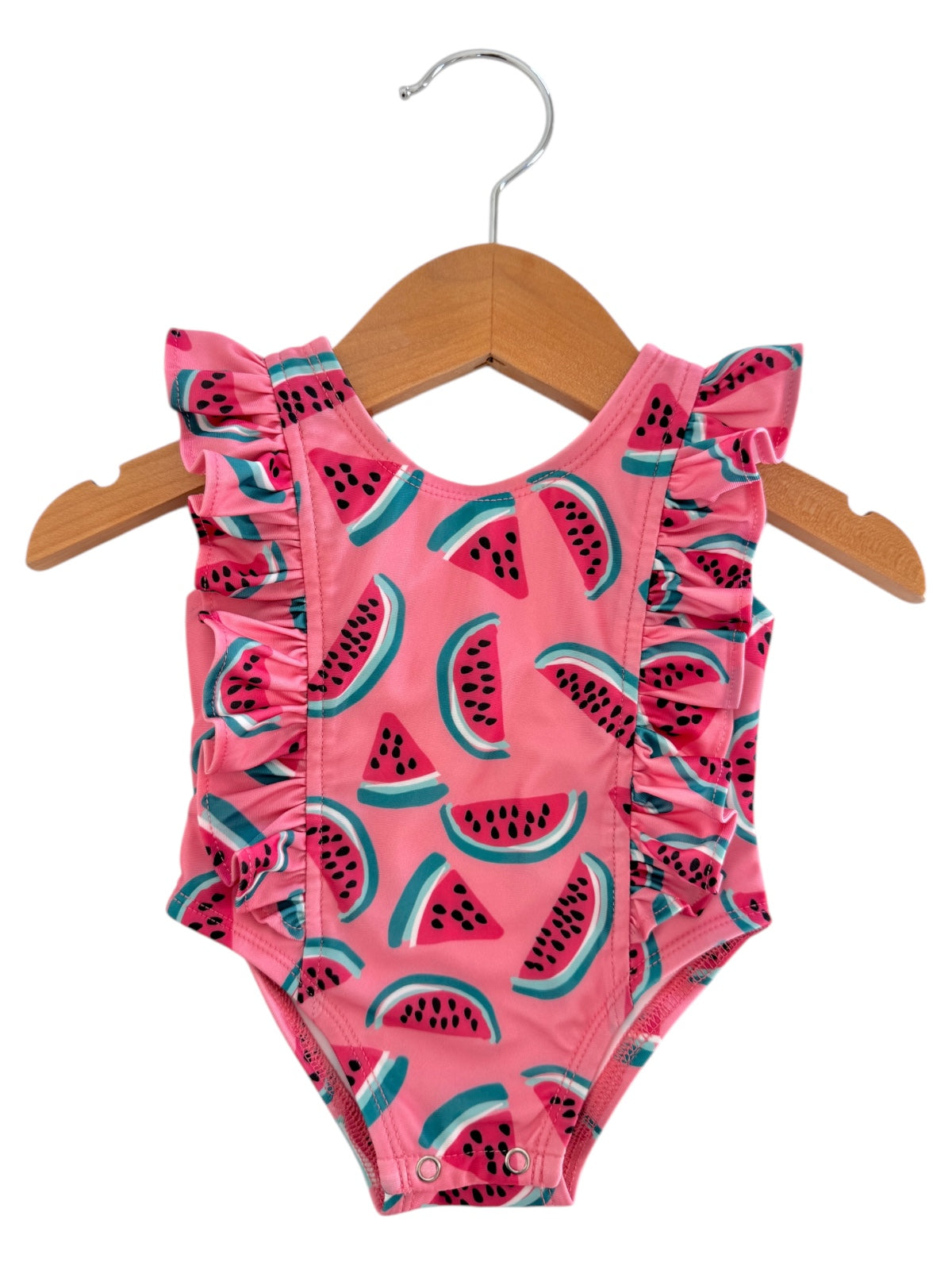 Pink baby swimsuit with ruffled straps, featuring a fun watermelon print on a wooden hanger.