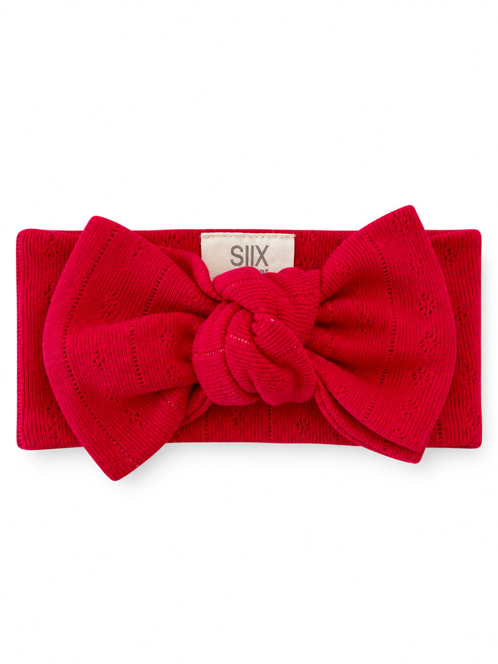 Red textured headband with a large bow detail and a knotted center, ideal for stylish hair accessories.