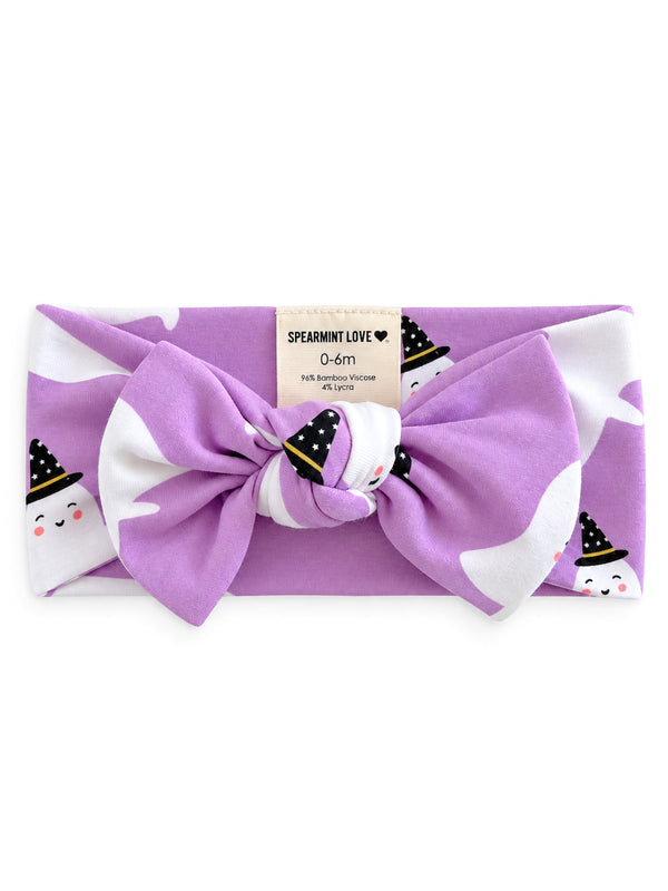 Purple headband with ghost and witch hat pattern, featuring a large bow and soft fabric. Brand label included.