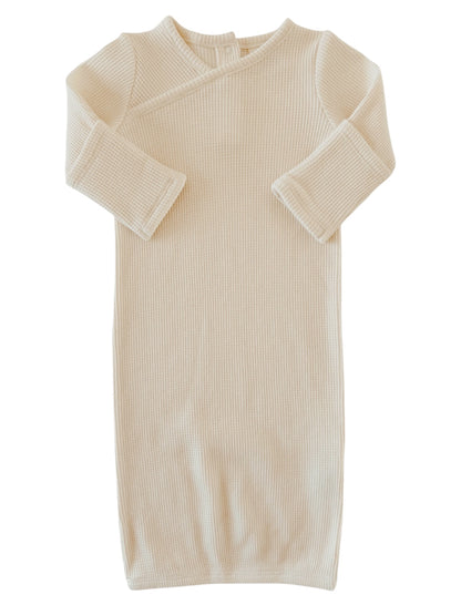 Cream-colored ribbed baby gown with long sleeves and a wrap design. Ideal for comfort and easy dressing.