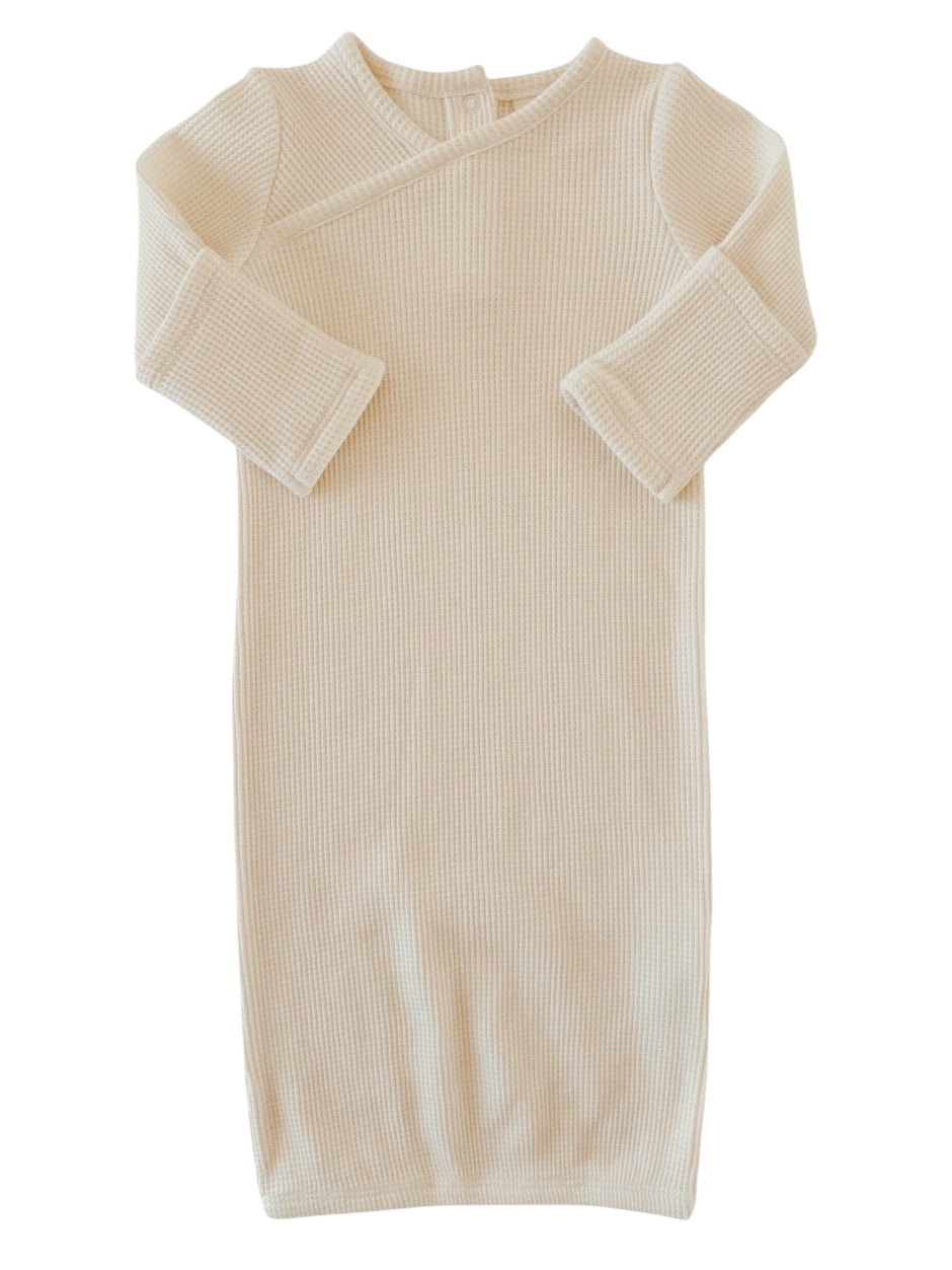 Cream-colored ribbed baby gown with long sleeves and a wrap design. Ideal for comfort and easy dressing.