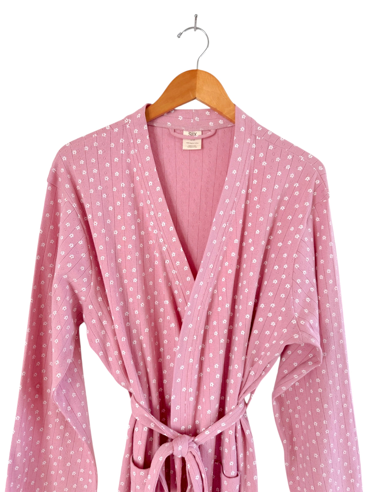 Pink floral-patterned robe hanging on a wooden hanger against a white background.