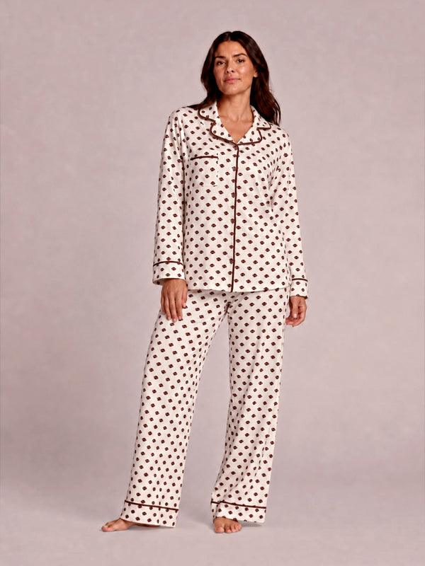 Woman in polka dot pajamas poses confidently against a light background. Casual, cozy sleepwear fashion.