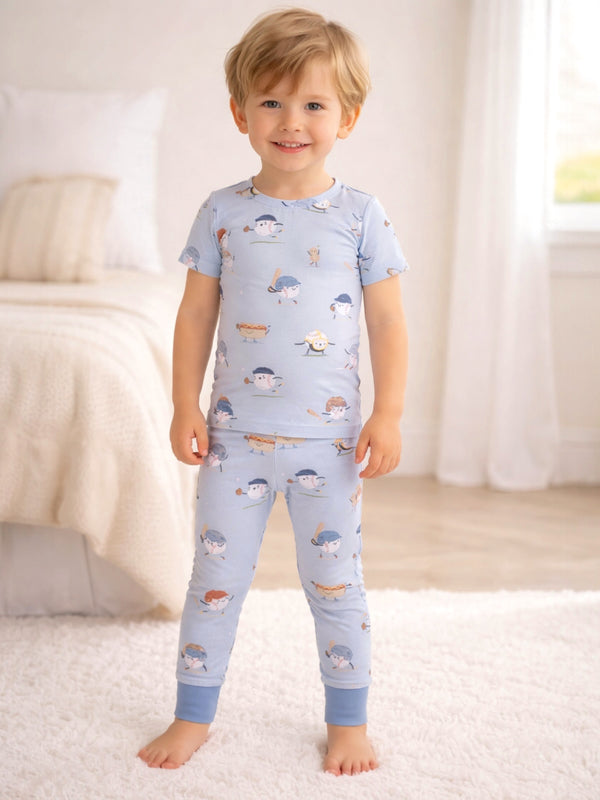 Smiling young boy in playful pajamas with cartoon patterns, standing in a bright, cozy bedroom.