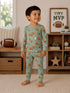 Smiling child in printed pajamas with playful designs, standing in a cozy living room with a football and decor.