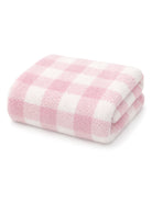 Soft pink and white checkered towel folded neatly. Ideal for cozy home decor or bath use.