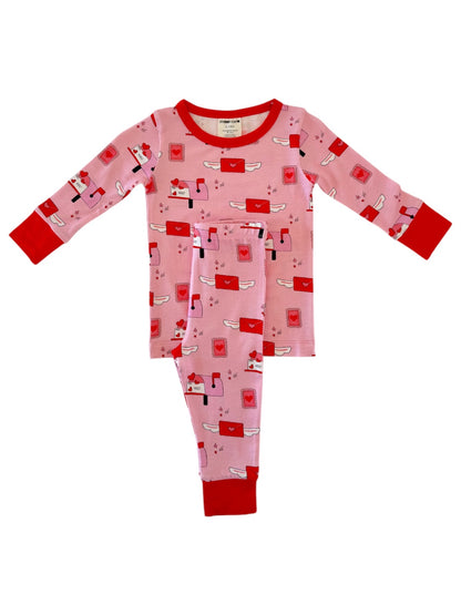 Pink pajamas with red accents featuring a playful mail theme and whimsical envelopes printed throughout.