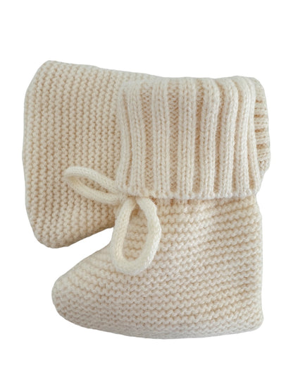 Cozy cream-colored knitted baby booties with a ribbed cuff and tie detail.