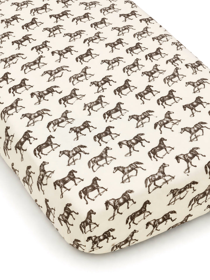 Horse-patterned crib sheet featuring repeated brown silhouettes on a cream background. Ideal for equestrian-themed nurseries.