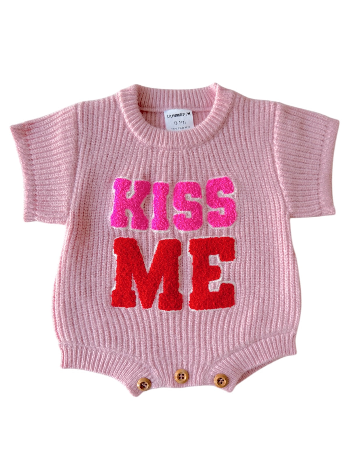 Pink baby romper with "KISS ME" in bold, colorful letters at the front. Short sleeves and button closure at the bottom.