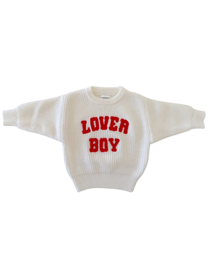 White sweater with red text that reads "LOVER BOY" on the front, featuring a ribbed design and wide sleeves.