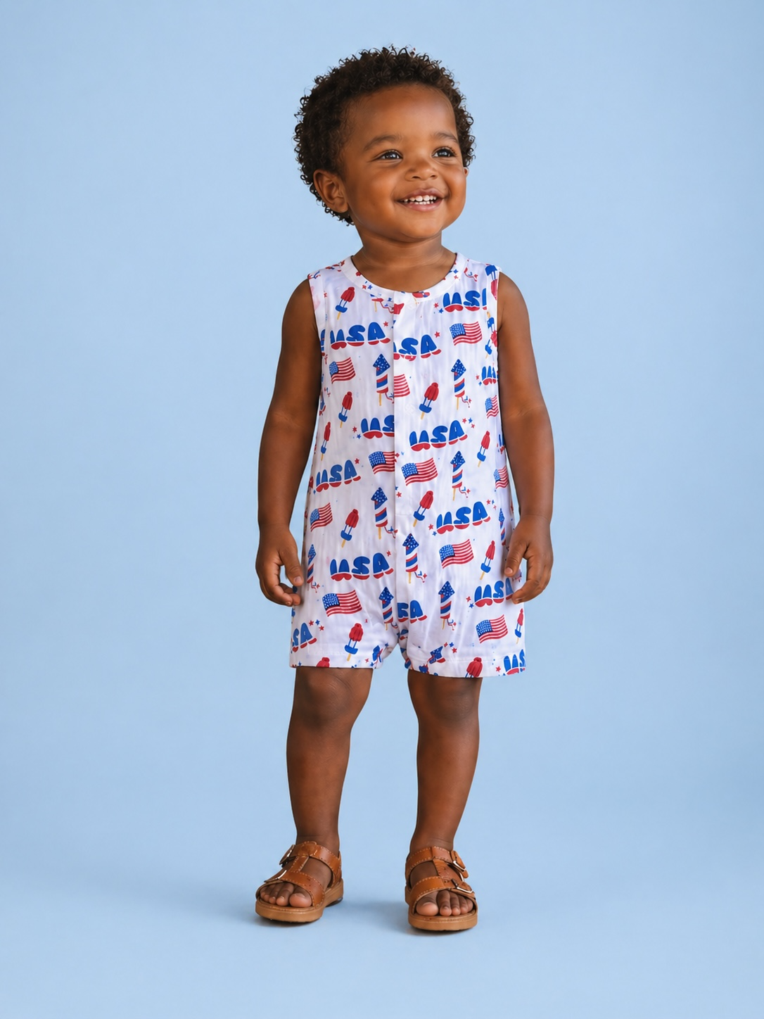 Smiling child in a colorful NASA-themed romper, standing on a light blue background.