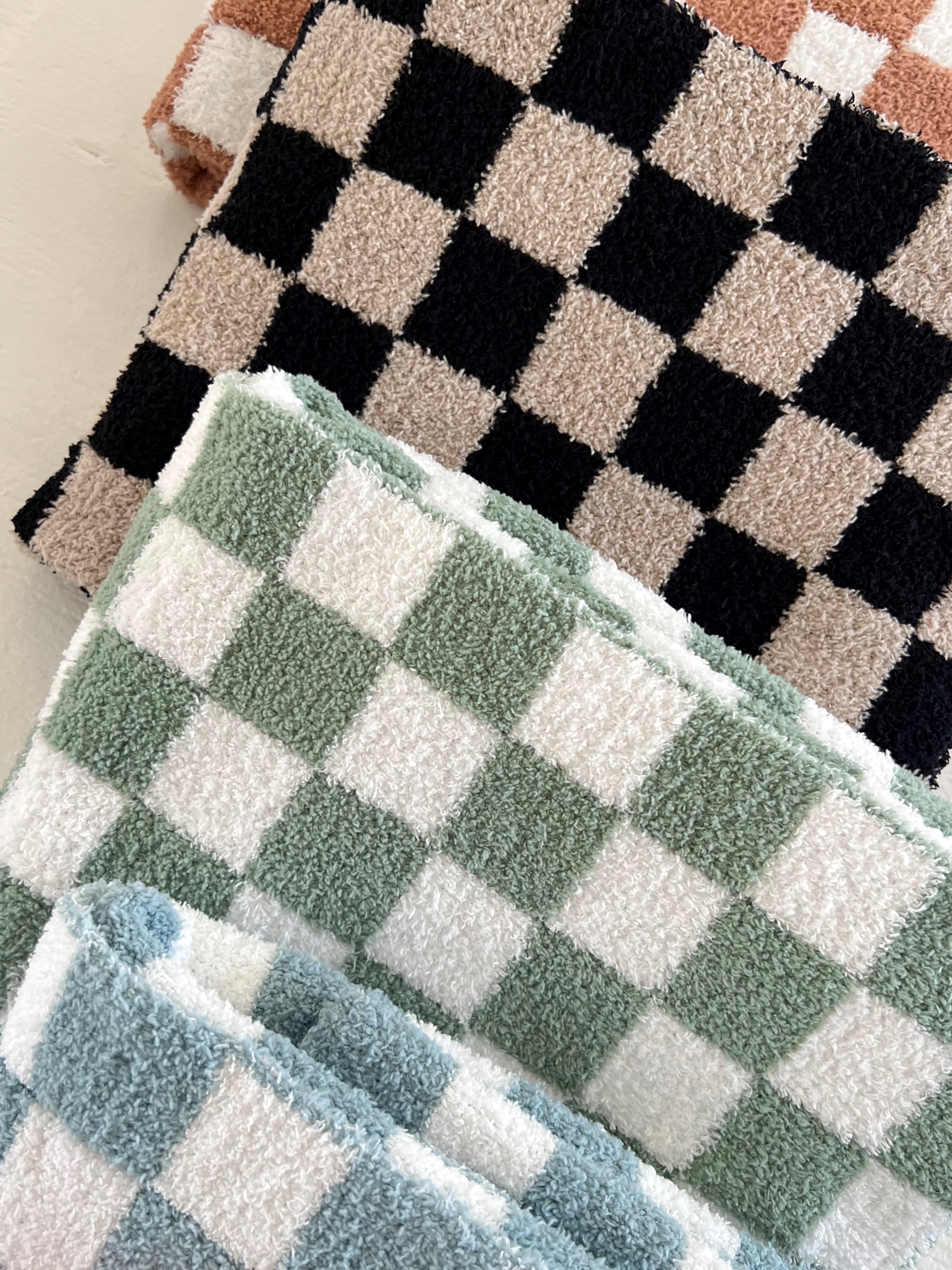 Checkered towels in various colors: black, beige, green, and blue stacked neatly.