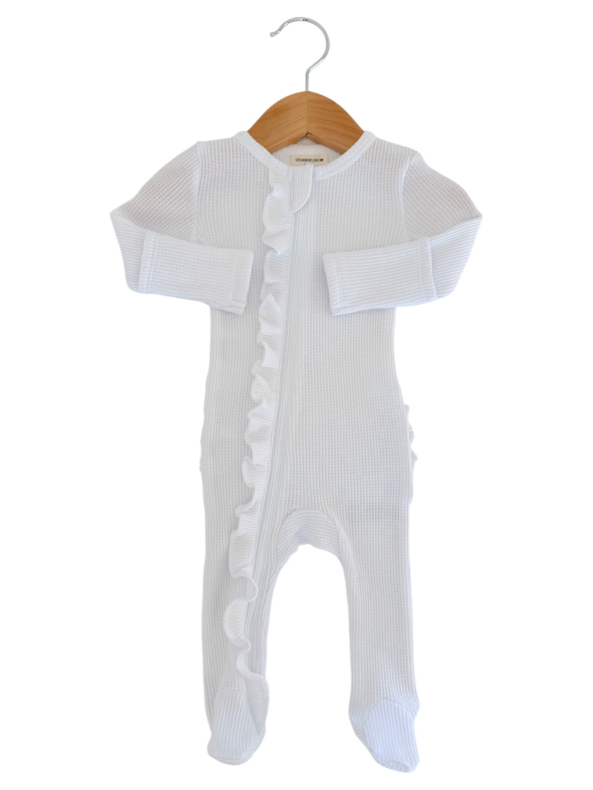 White baby onesie with ruffle detailing, hanging on a wooden hanger against a white background.