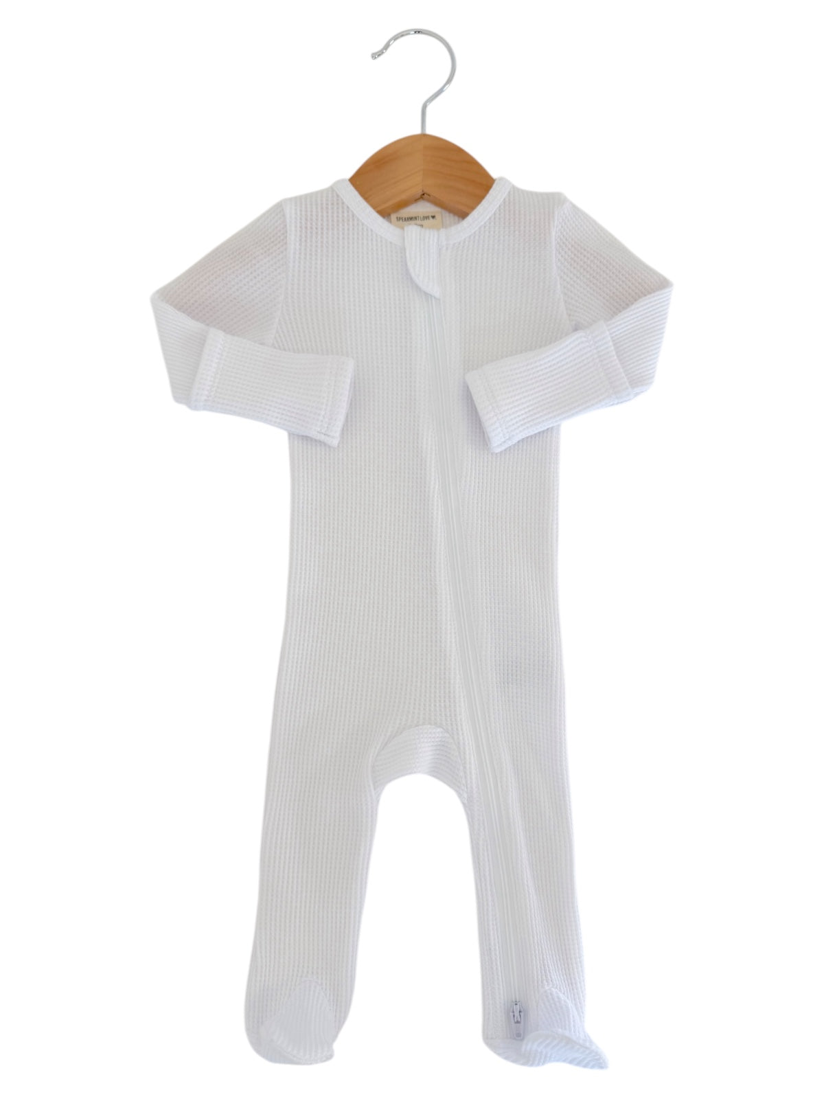White infant onesie with long sleeves, zipper closure, and footed design, displayed on a wooden hanger.