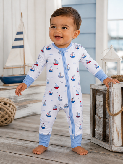 Happy toddler in a boat-patterned pajama, standing on wooden floor near toys and decor in a bright, airy room.