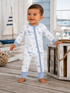 Smiling toddler in whale-patterned pajamas, standing on wooden floor with nautical decor.