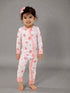 Smiling child in pink floral pajamas with a bow, standing on a gray background.