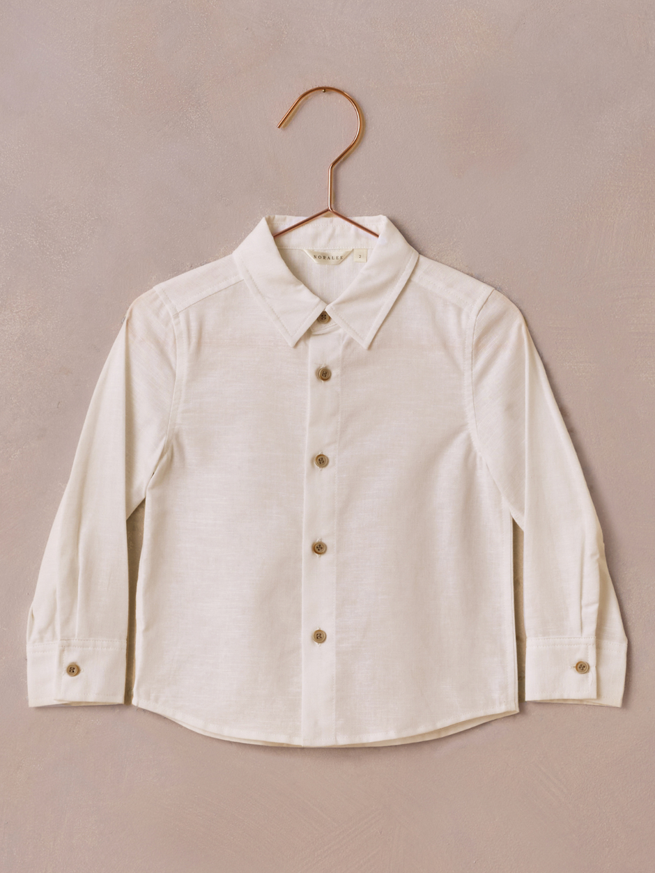 Light-colored long-sleeve button-up shirt hanging against a textured background.