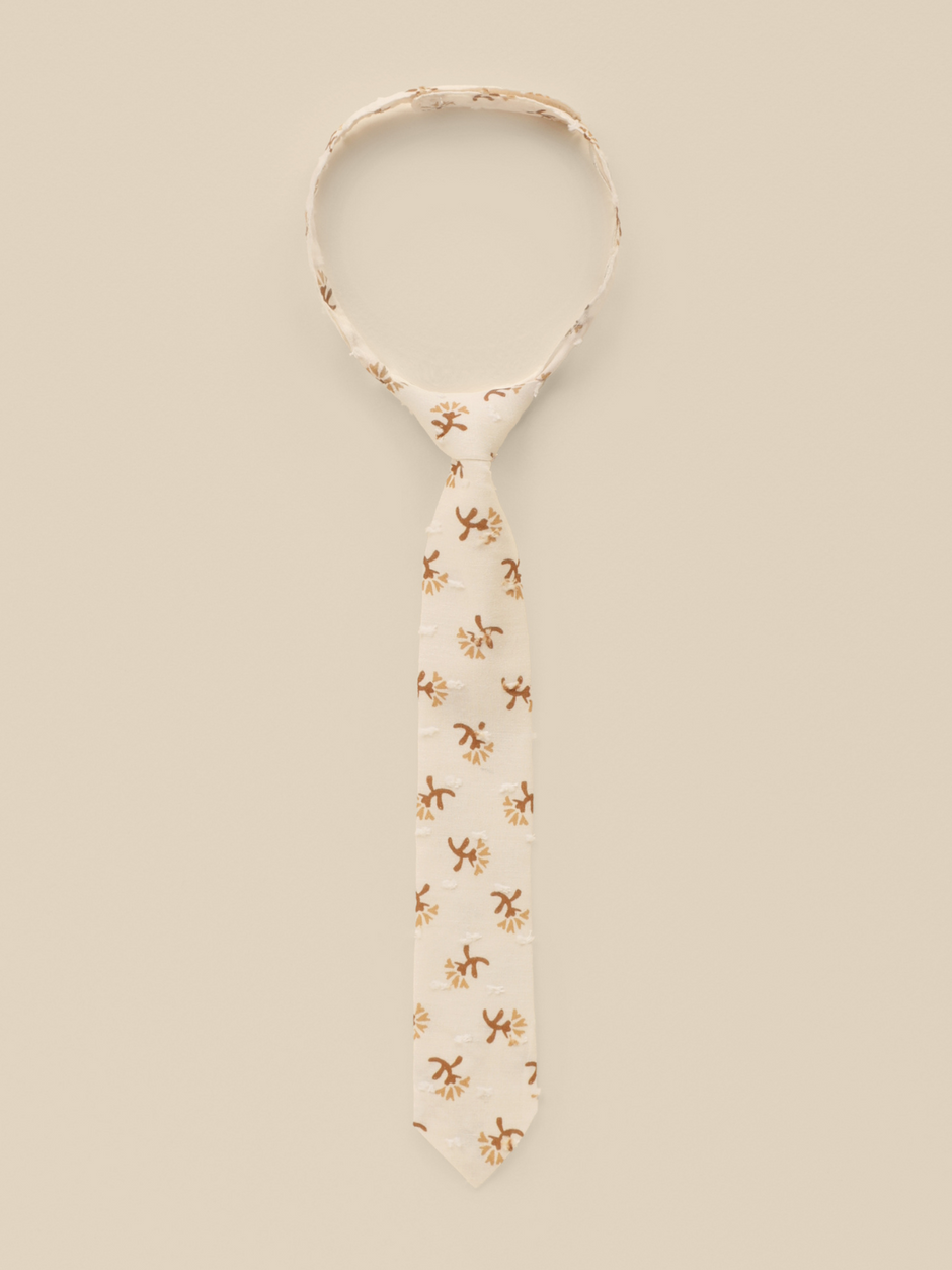 Beige tie with floral patterns on a light background, elegantly displayed for a stylish look.