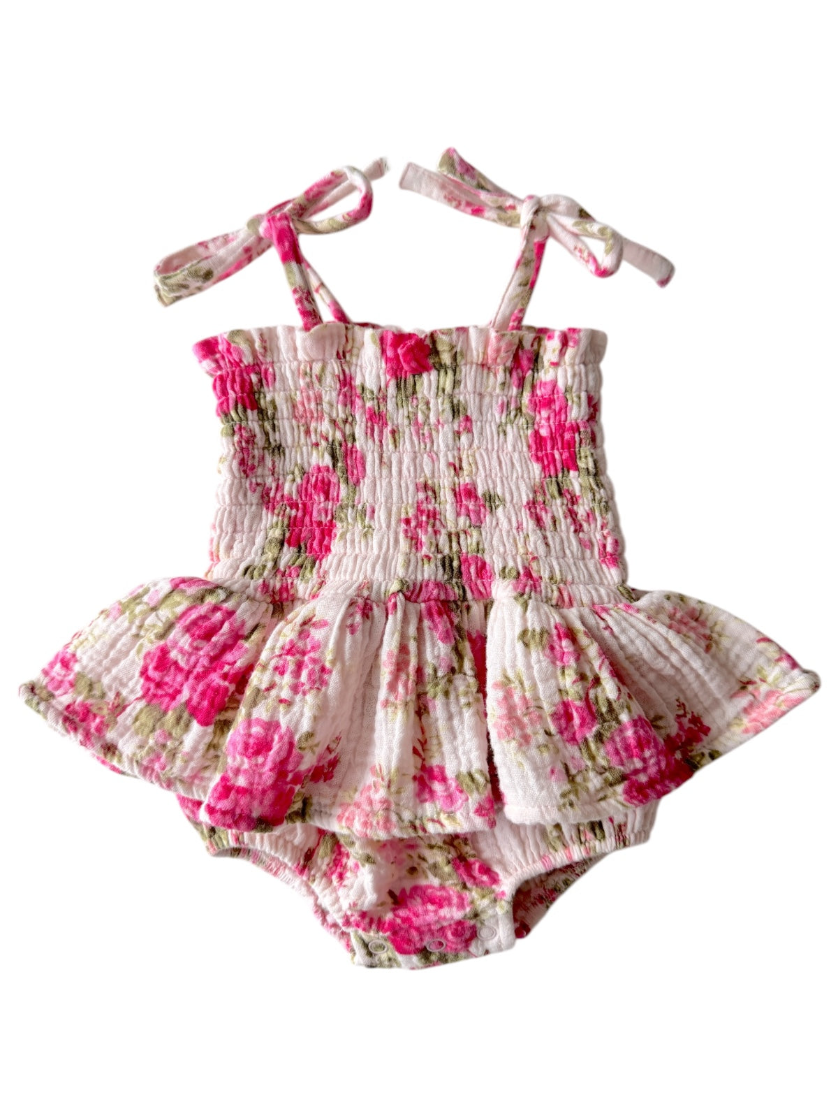 Floral baby romper with pink and green flowers, featuring shoulder ties and a ruffled skirt.