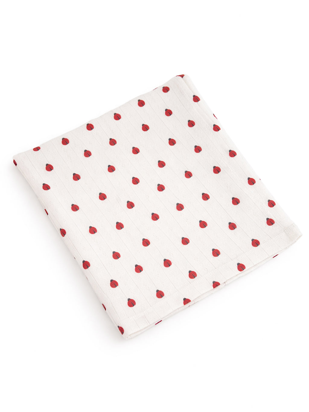 White fabric with a pattern of small red dots, folded neatly on a flat surface.