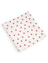 White fabric with a pattern of small red dots, folded neatly on a flat surface.