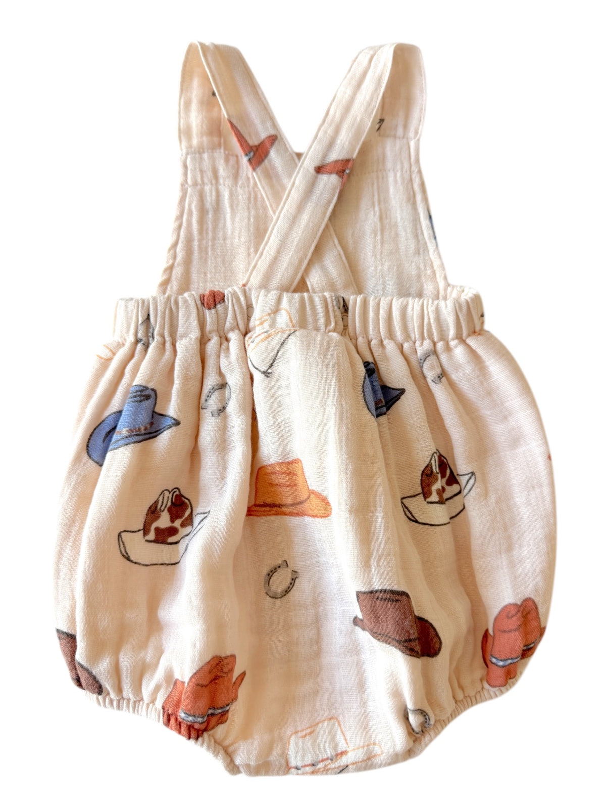 Children's romper with a pale background and colorful hat patterns, featuring crisscross straps.