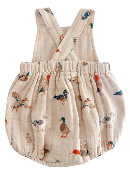 Light beige children's romper with duck illustrations and crossed straps. Ideal for playful outfits.
