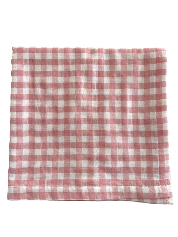Pink and white checkered fabric laid flat, showcasing a classic gingham pattern. Ideal for home decor or crafting.