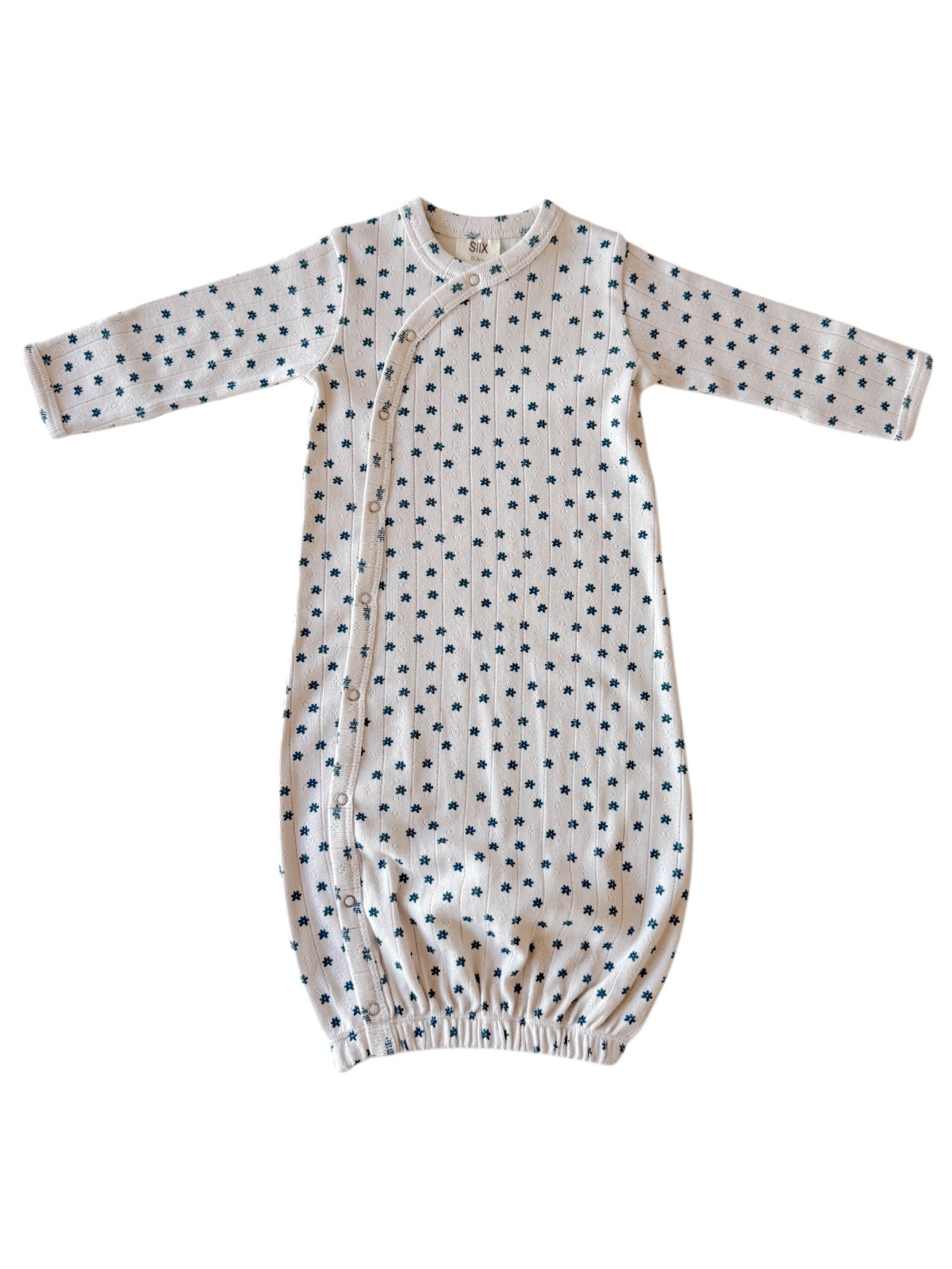 Light-colored baby gown with long sleeves and small navy floral print, featuring snap closures along the side.