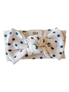White headband with a large bow and dotted floral pattern in blue, labeled with brand name "SIIX."