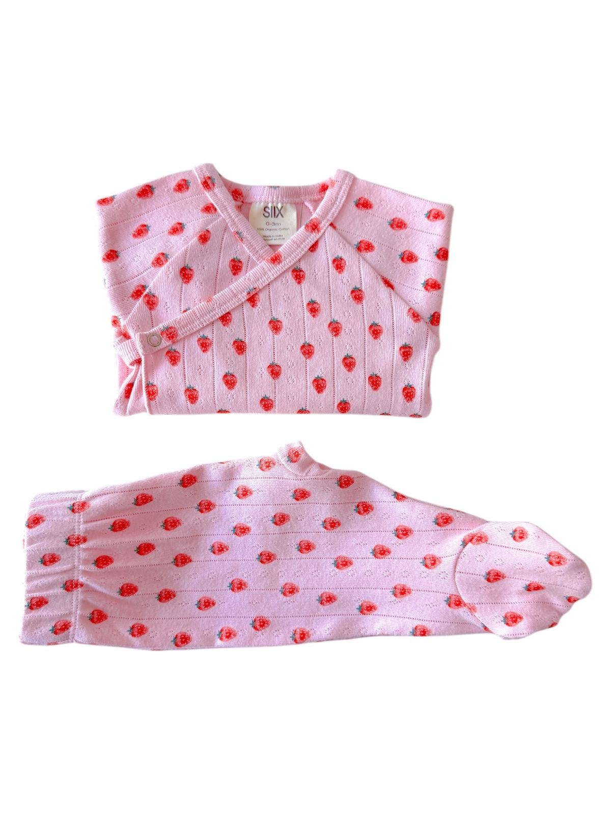 Light pink baby outfit featuring a cross-over top and pants with red strawberry patterns.