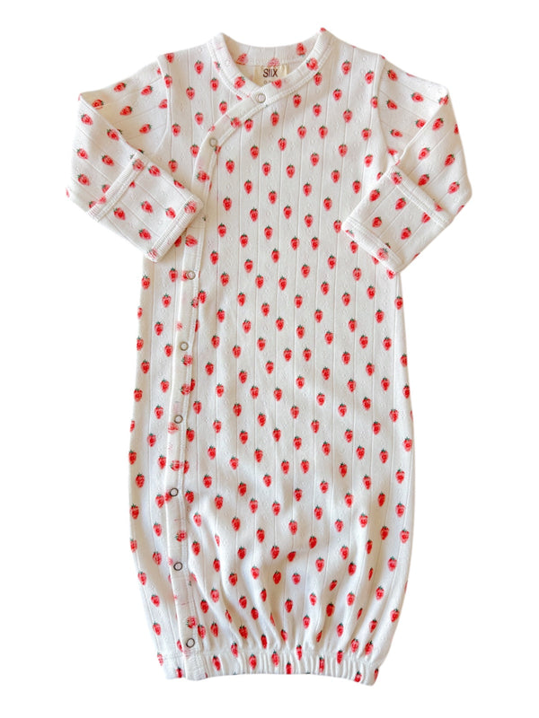 White baby gown with red strawberry pattern, featuring long sleeves and snap buttons along the side.
