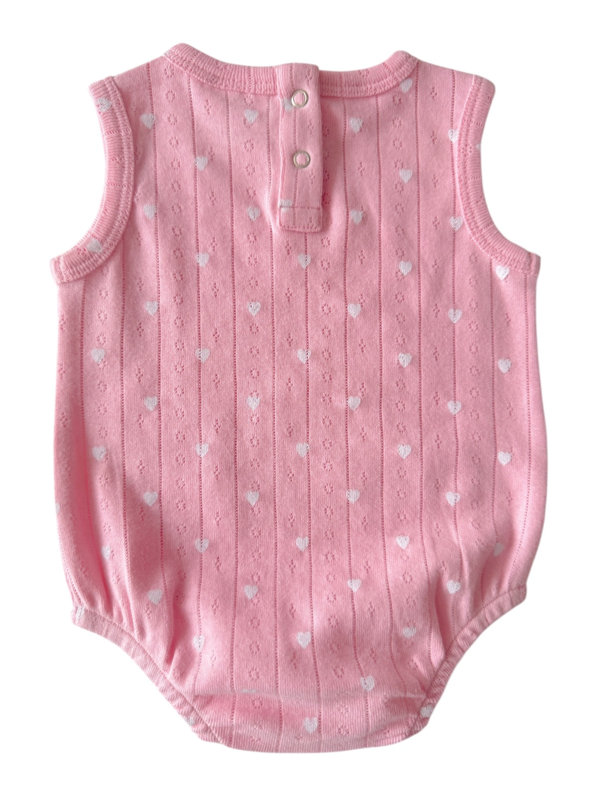 Pink sleeveless baby romper with white heart patterns and button closure at the back.