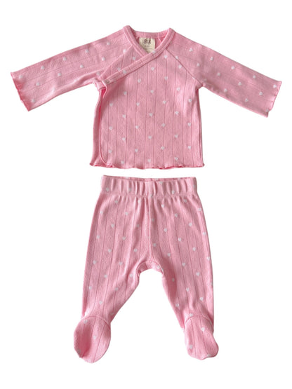 Pink baby outfit featuring a long-sleeve top and matching pants, both with white polka dot patterns.