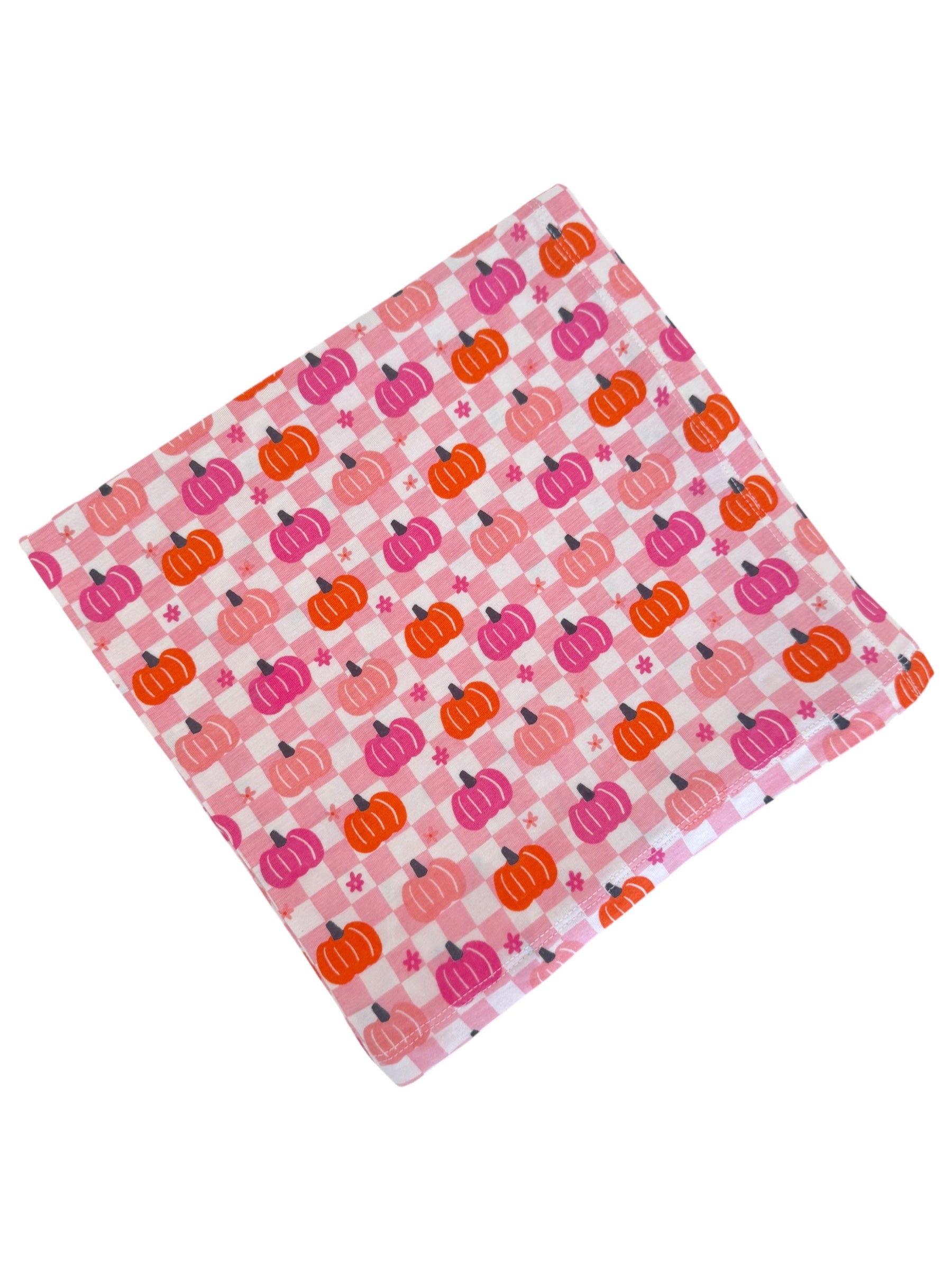 Colorful fabric square featuring a pumpkin and checkered pattern in pink and orange hues.