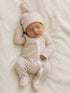 Newborn baby in a striped onesie and matching hat, peacefully sleeping on a soft, light-colored blanket.