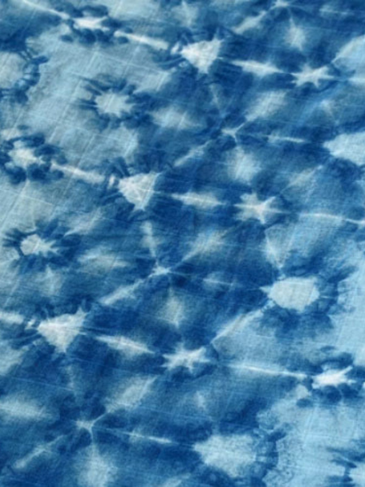 Close-up of a blue tie-dye fabric with a starburst pattern and varying shades of blue and white.