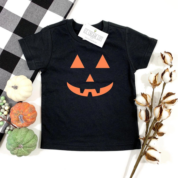 Black toddler t-shirt featuring an orange jack-o'-lantern design, surrounded by decorative pumpkins and cotton stems.