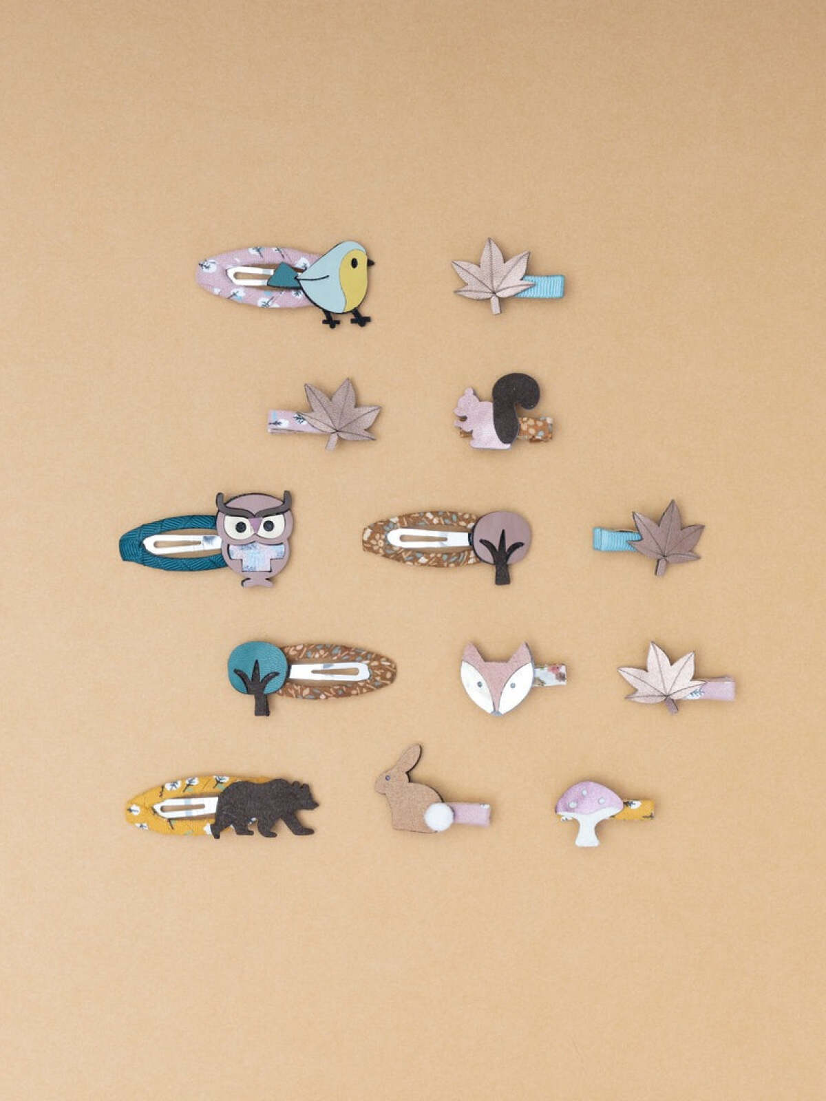 Assorted hair clips featuring animals and leaves on a beige background.