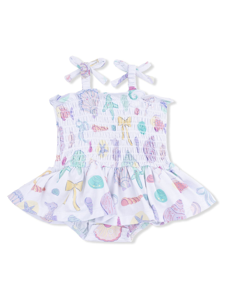 Girls' swim dress with pastel seashell print and bow straps, featuring a flared skirt and matching bottom.