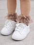White sneakers with frilly, pink heart-patterned ankle socks on a child's feet.