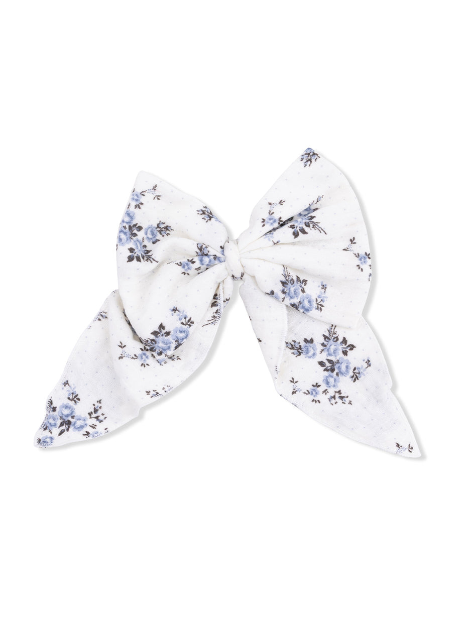 Floral patterned hair bow in white and blue fabric, tied in a large bow shape.